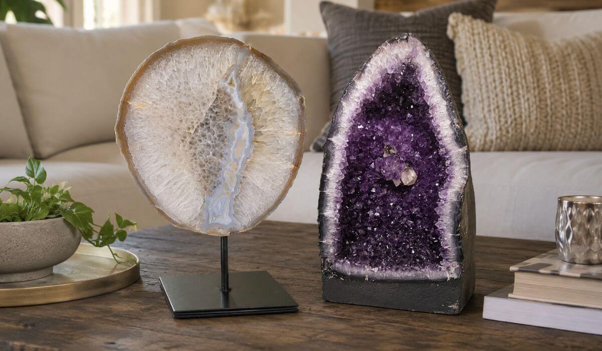 Agate geode slice and amethyst geode displayed side by side on a wooden coffee table